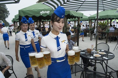 This photo taken on August 12, 2016 shows a waitress carrying jugs of beer to guests before the opening of the Pyongyang Taedonggang Beer Festival on the banks of the Taedong river in Pyongyang. / AFP / Kim Won-Jin        (Photo credit should read KIM WON-JIN/AFP/Getty Images)